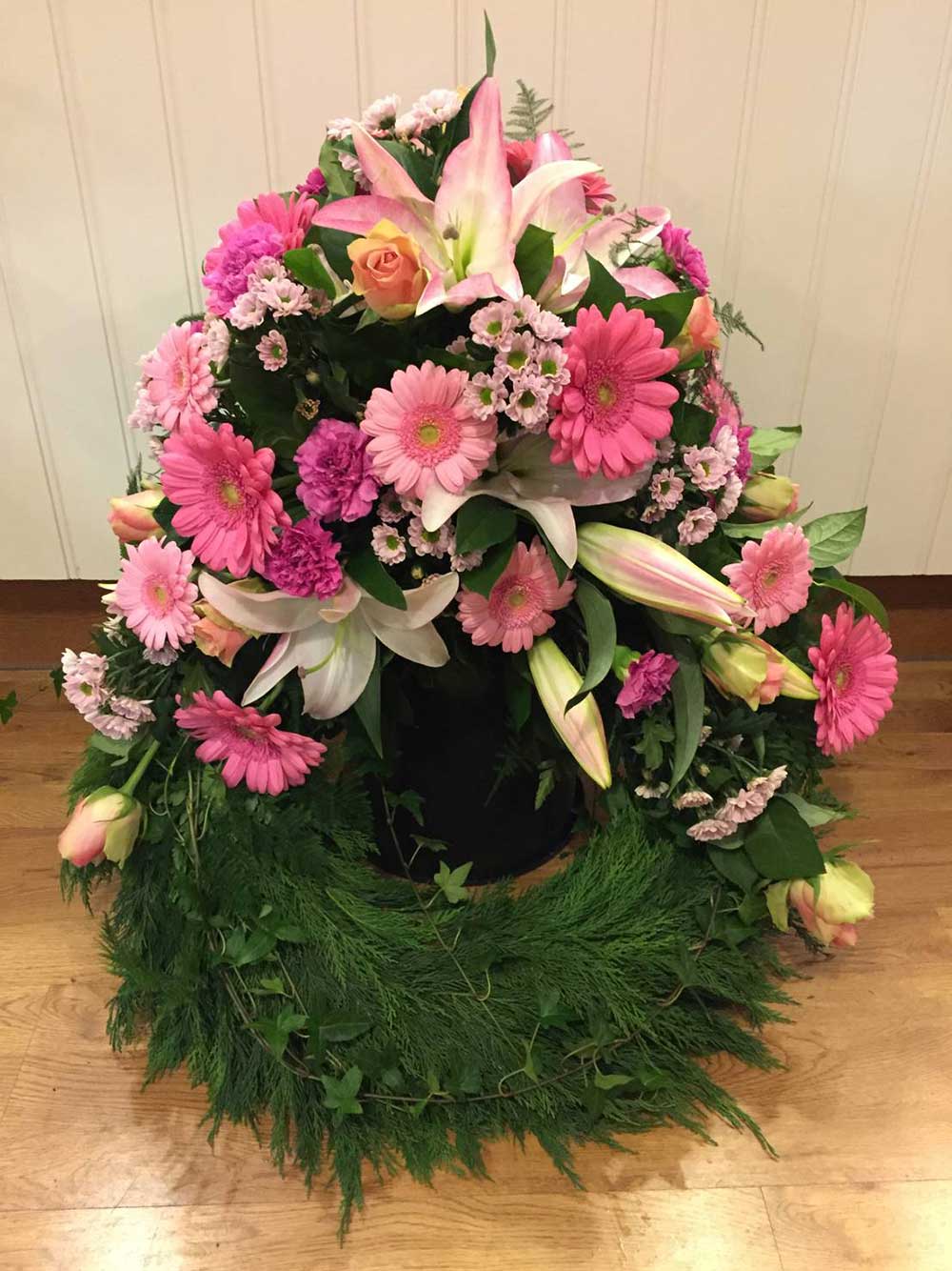 Begravningskrans med rosa liljor och andra rosa blommor